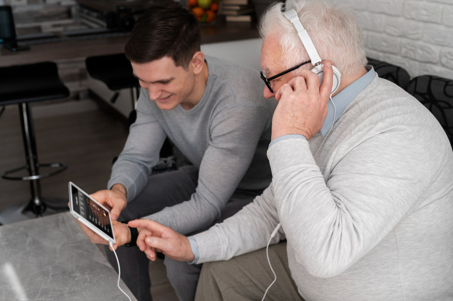 Grandson helping grandfather take online hearing test.